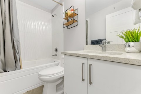 A white bathroom with a toilet, sink, and a mirror.