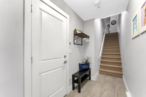 A hallway with a staircase and a table with a plant on it.