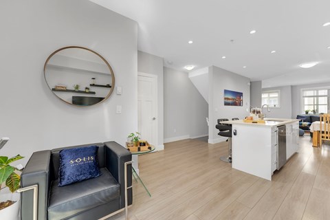 A modern living room with a grey sofa and a round mirror on the wall.