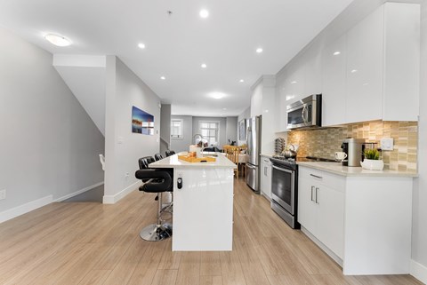 A modern kitchen with white cabinets and a wooden floor.