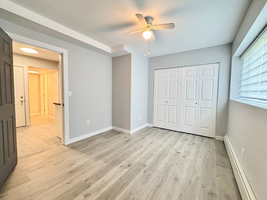 A room with a ceiling fan and a white door.
