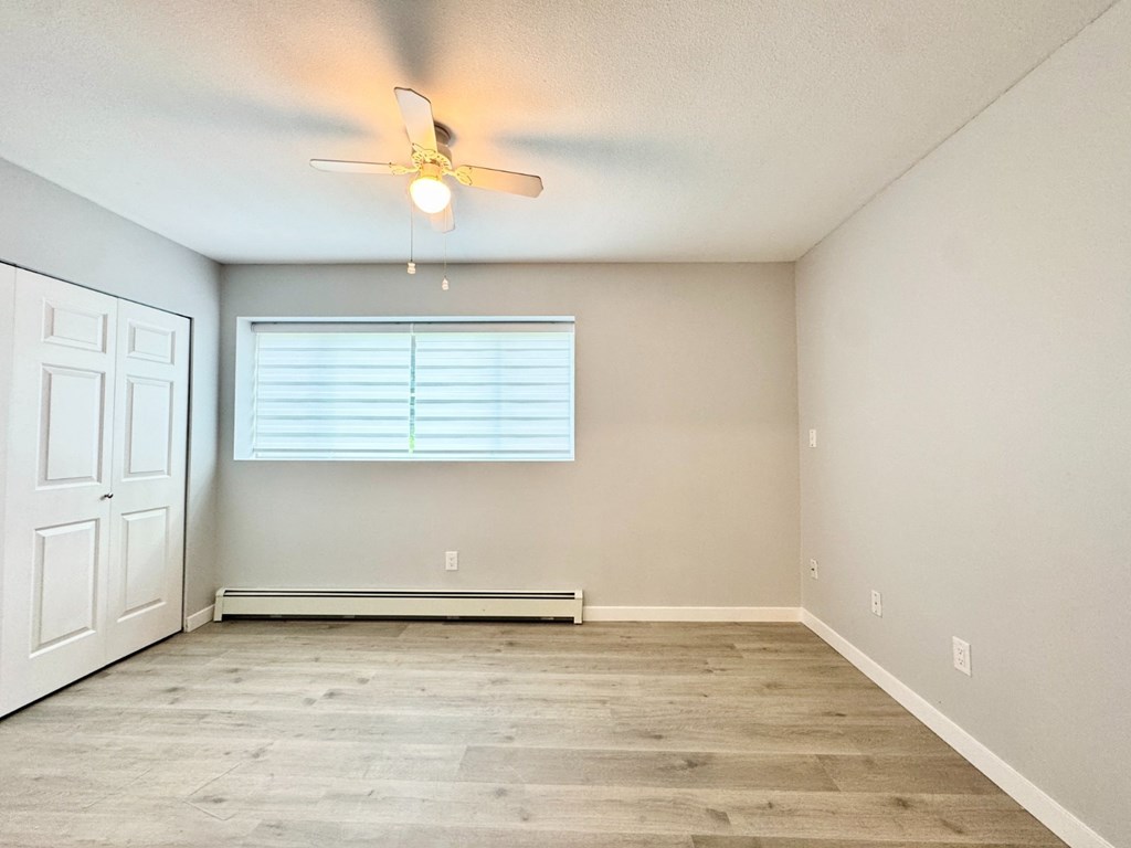 A room with a ceiling fan and a window with blinds.