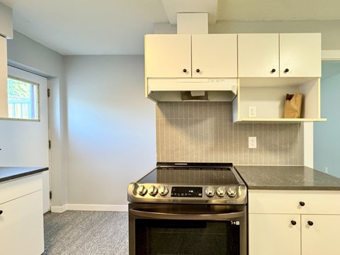 A kitchen with a stove top oven and cabinets.