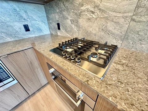 A modern kitchen with a granite countertop and a stainless steel gas stove.
