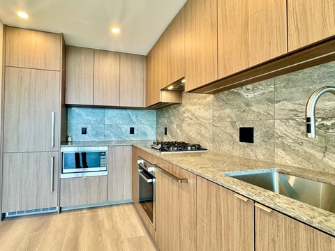A kitchen with wooden cabinets and a marble backsplash.