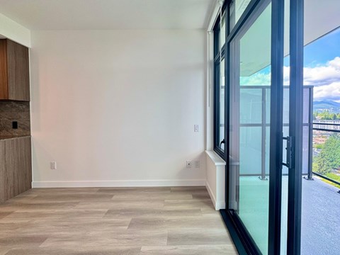 A room with a wooden floor and a glass door leading to a balcony.