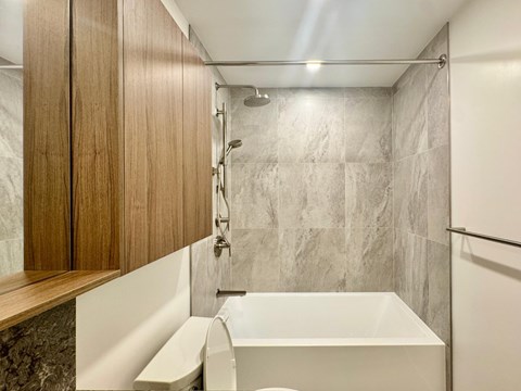 A modern bathroom with a white tub and wooden cabinets.