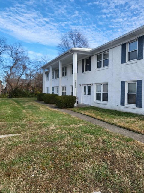 A white two-story building with blue trim and a small front yard.