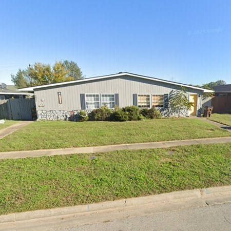 A grey building with a green lawn in front.