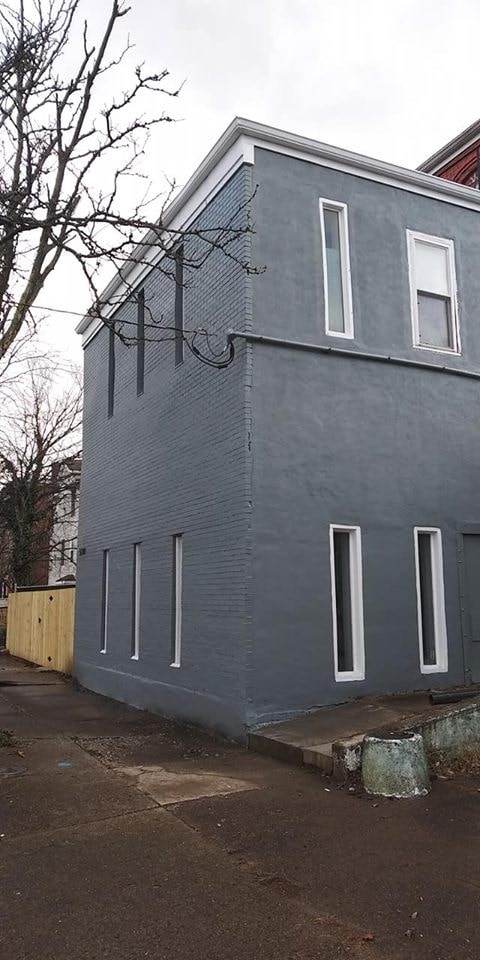 A grey building with a tree in front of it.