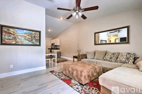 A living room with a couch, ottoman, and a painting on the wall.
