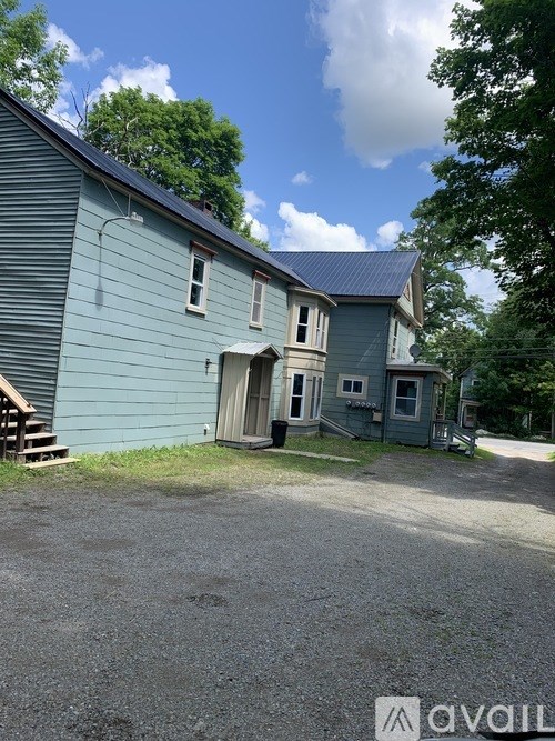 A blue house with a gravel driveway in front.