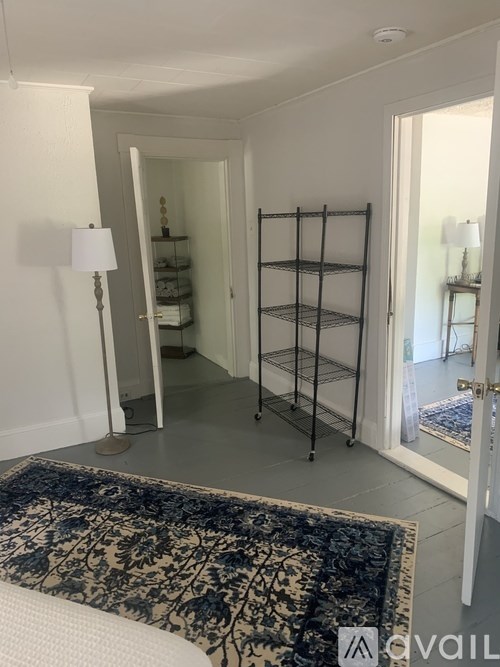 A hallway with a rug and a shelf with a mirror.