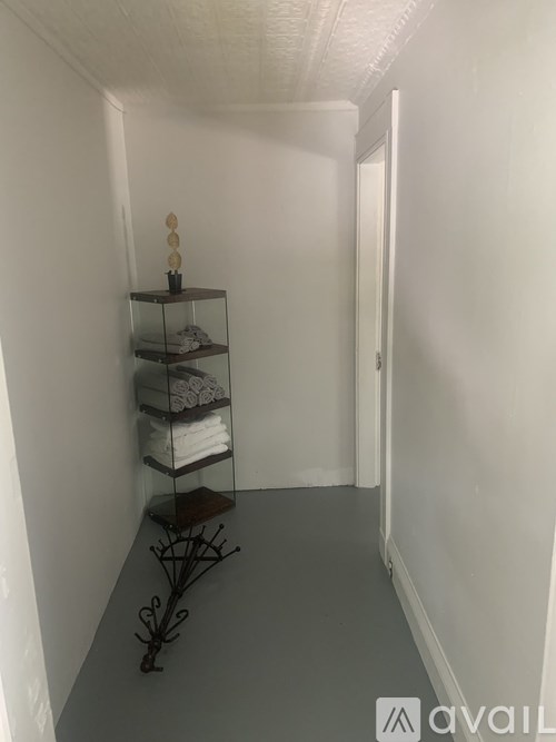 A white hallway with a shelf and a chair.