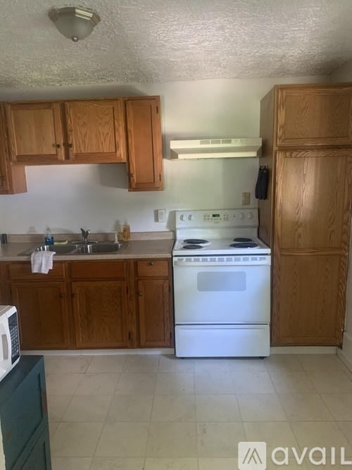 A kitchen with wooden cabinets and a white stove top oven.