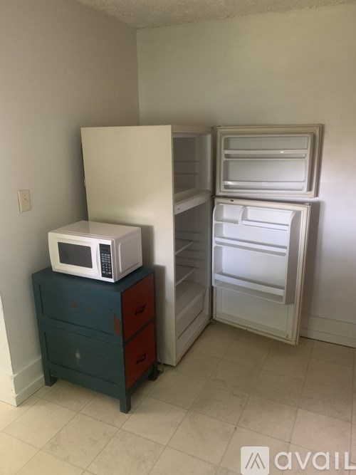A white microwave is on top of a blue cabinet.
