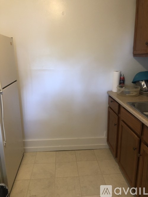 A kitchen with a refrigerator, sink, and cabinets.
