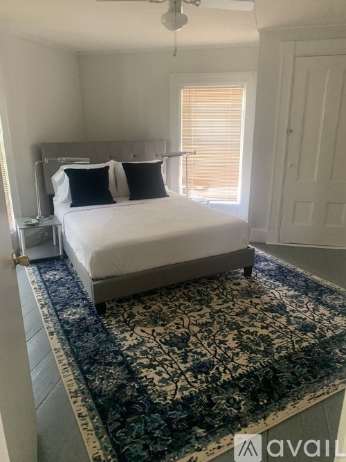 A bedroom with a large bed and a patterned rug.