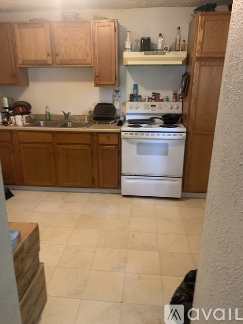 A kitchen with a white stove top oven and wooden cabinets.