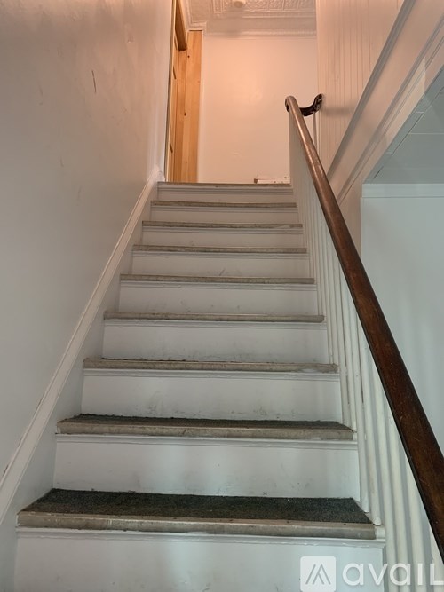 A staircase with a wooden handrail and white steps.