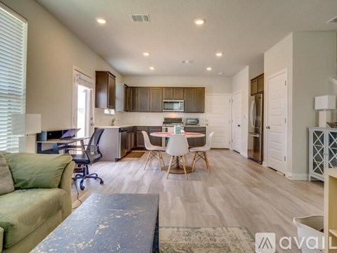 A well-lit, spacious kitchen and living room with a dining table and chairs.