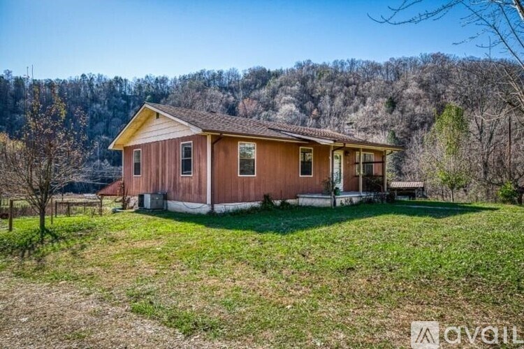 A house with a brown roof and a yellow trim is surrounded by a grassy field.