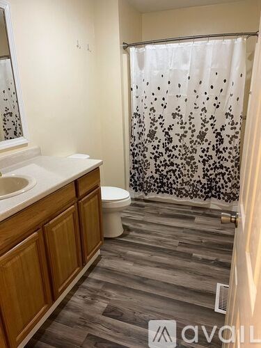 A bathroom with a wooden vanity and a shower curtain with a black and white pattern.