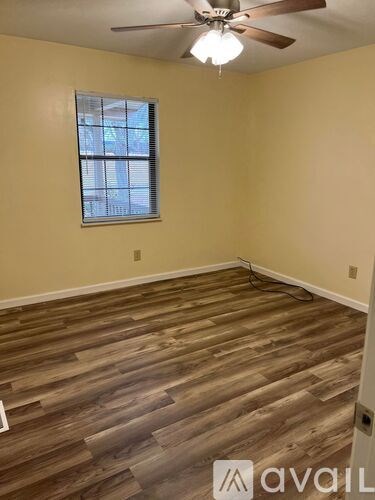 A room with wooden flooring and a ceiling fan.