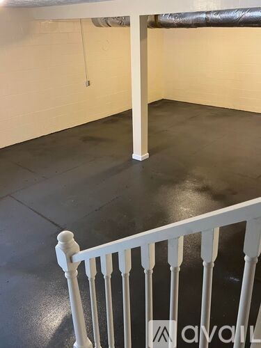A white railing in a room with a black floor.