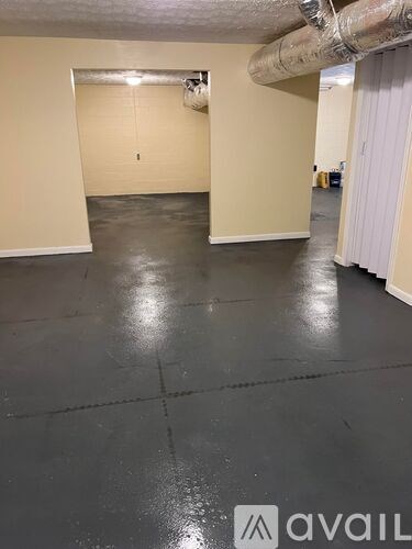 A spacious room with a grey floor and a white door.