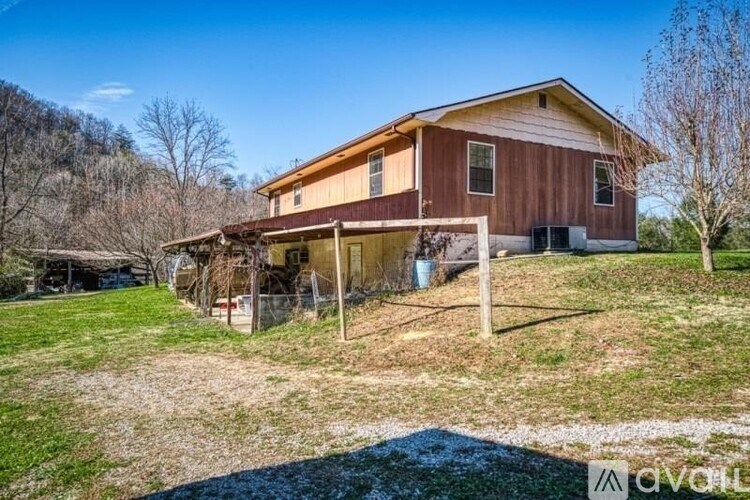 A house with a brown and beige exterior is surrounded by a grassy area and trees.