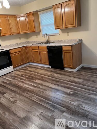 A kitchen with wooden cabinets and a black dishwasher.