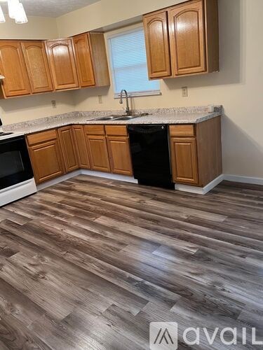 A kitchen with wooden cabinets and a black dishwasher.