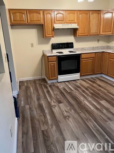 A kitchen with wooden cabinets and a white stove top oven.