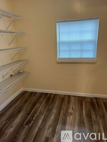 A room with a window and wooden flooring.