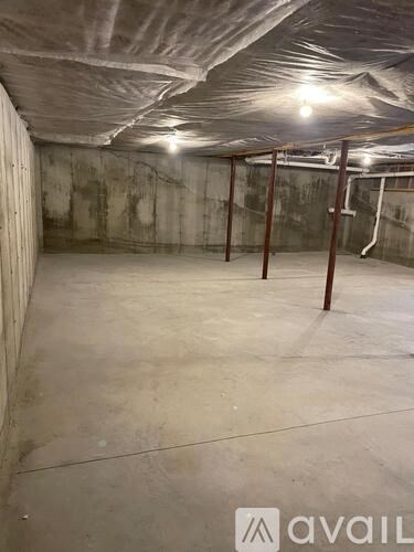 A spacious basement with concrete walls and floor, and a ceiling covered with insulation material.