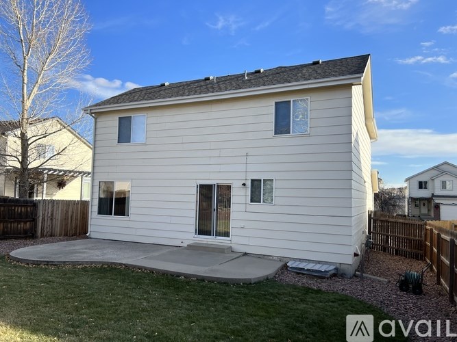 A white house with a grey roof and a small yard.