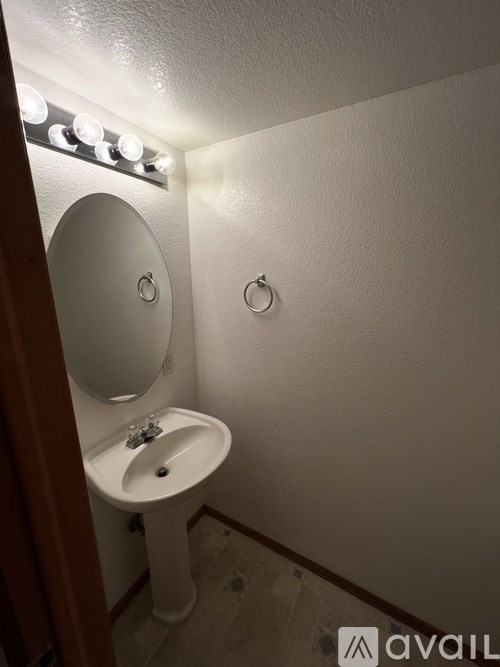 A small white sink under a mirror with lights above it.
