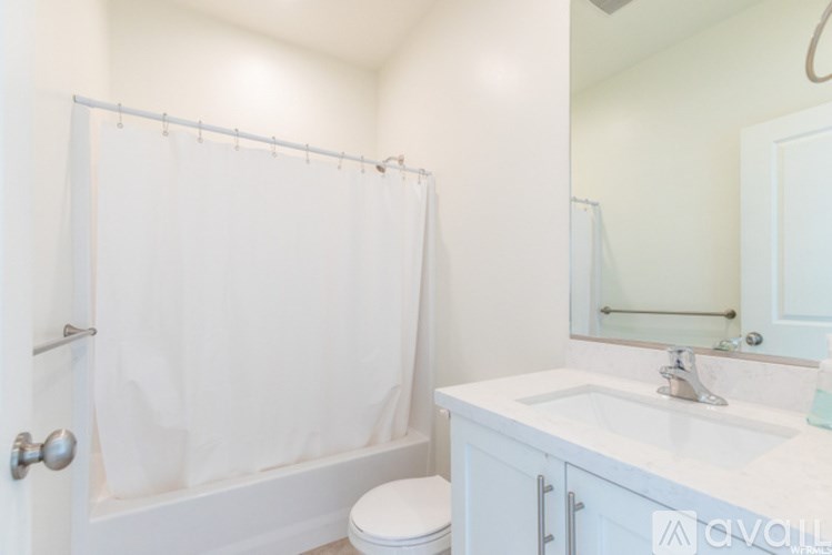 A white bathroom with a toilet, sink, and shower.