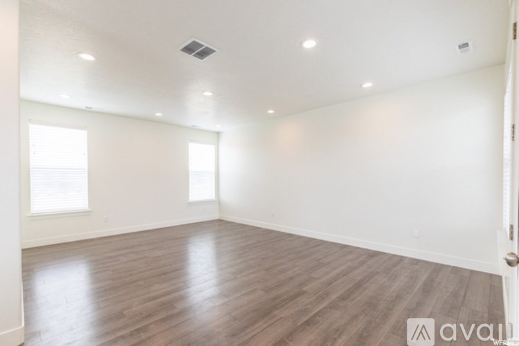 A spacious room with wooden flooring and white walls.
