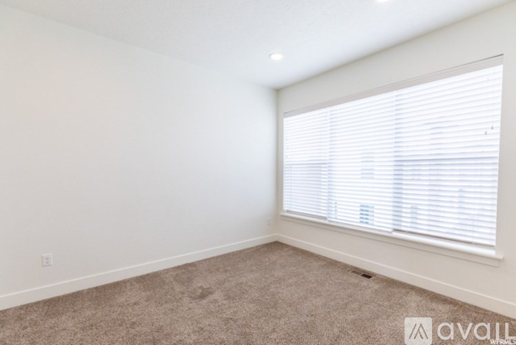 A room with a carpeted floor and a window with blinds.