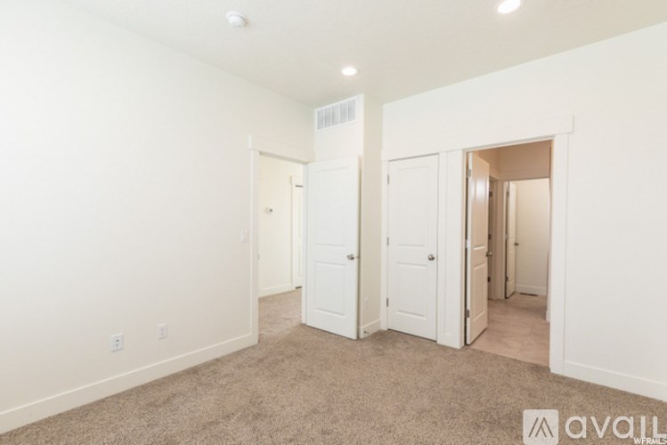 A room with white walls and carpeted floor with a door on the right.