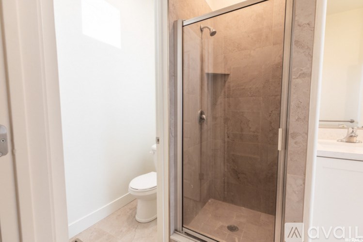 A bathroom with a toilet, a walk-in shower, and a sink.