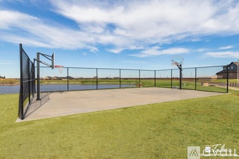 A basketball court with a fence and a basketball hoop.