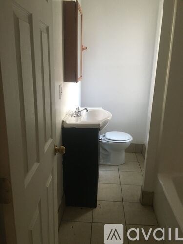 A bathroom with a toilet, sink and cabinet.