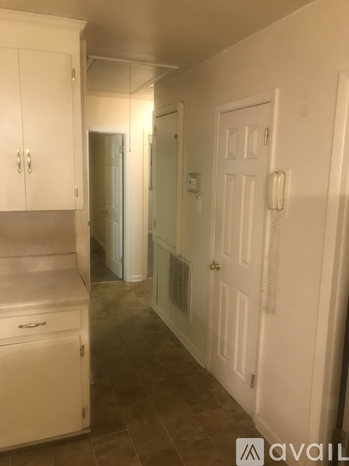 A hallway with a white door and a white cabinet.