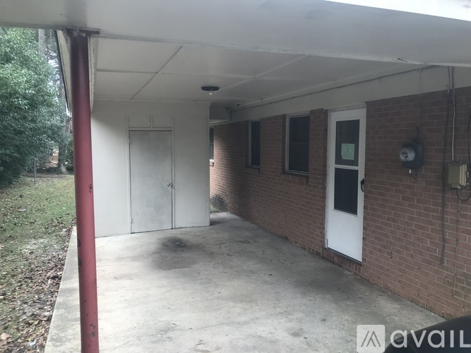 A white door is on the right side of a brick building.