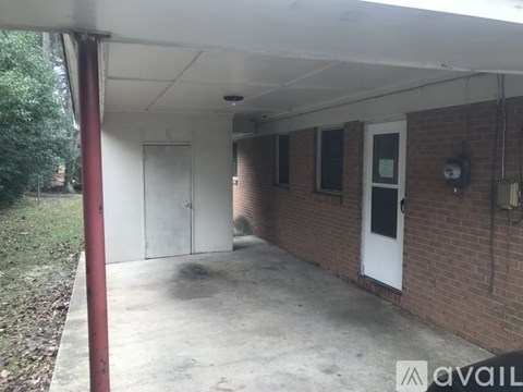 A white door is on the right side of a brick building.