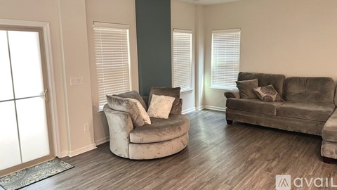 A living room with a grey couch and a white chair with a cushion.