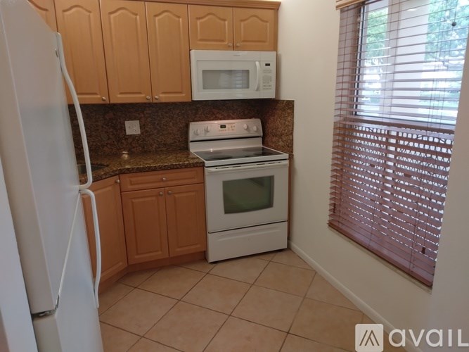 A kitchen with a white refrigerator, white microwave, white oven, and brown cabinets.